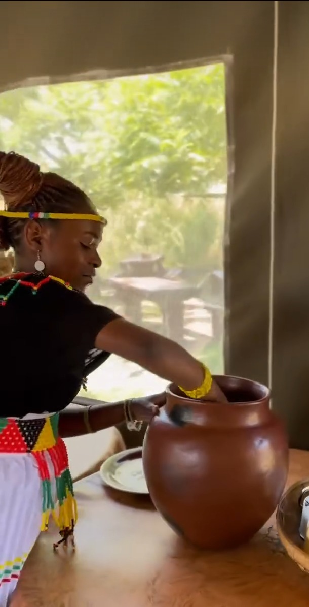 A staff member in traditional dress arranging a large clay pot