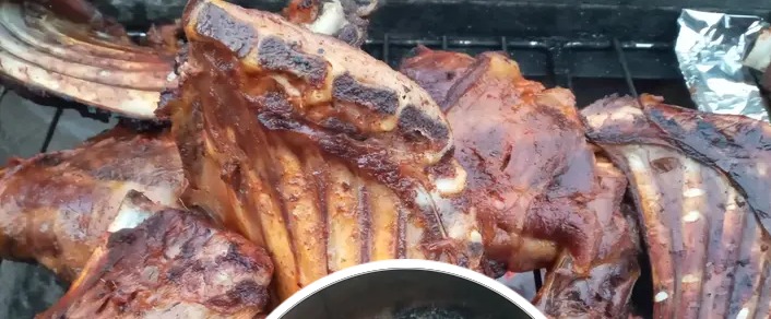 Ribs and cuts of meat charring over open charcoal