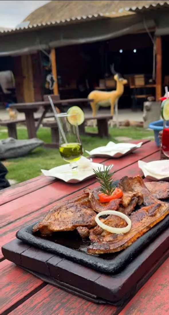 A grilled meat platter with rosemary garnish and cocktails, served in the evening garden