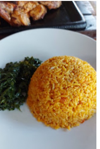 Jollof rice with greens on a white plate