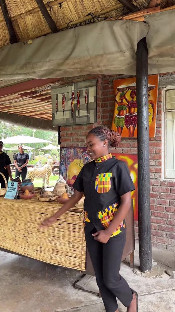 A staff member in branded uniform welcoming guests beside the curio display